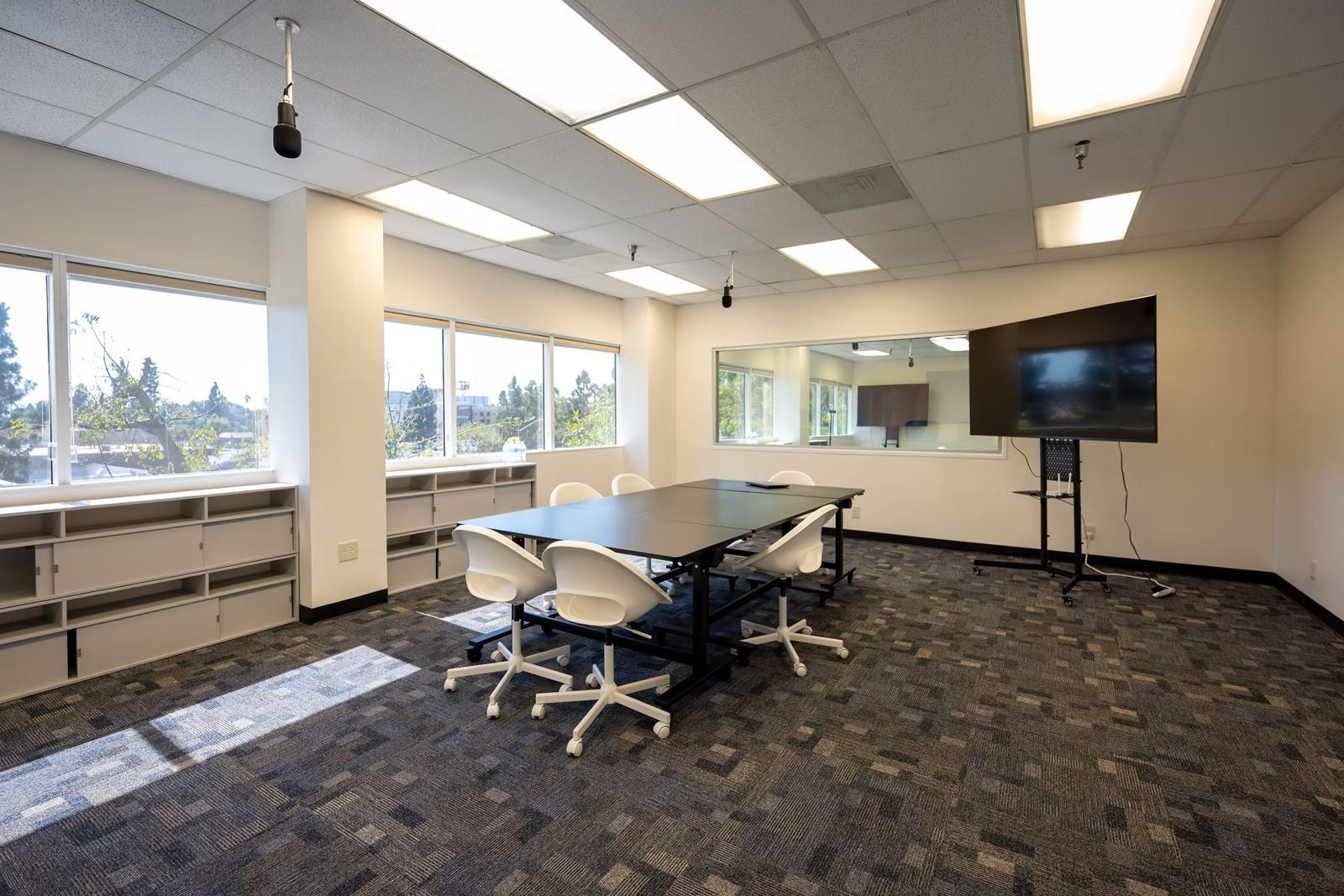 Suite A research room set up with a discussion table, screen and one-way mirror